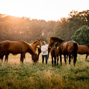 A woman bonding with horses in a field