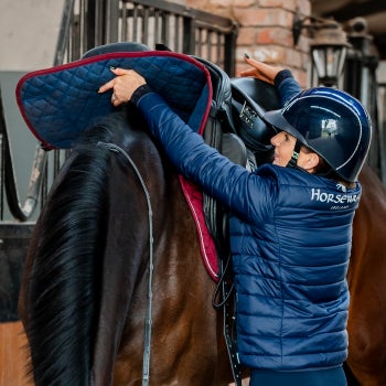 Rider Placing a Saddle on a Horse